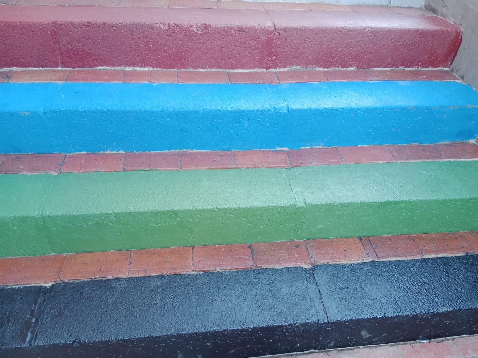 Escaleras impermeabilizadas y pintadas con Imperlluvia, vista frontal de los escalones en rojo, azul, verde y negro